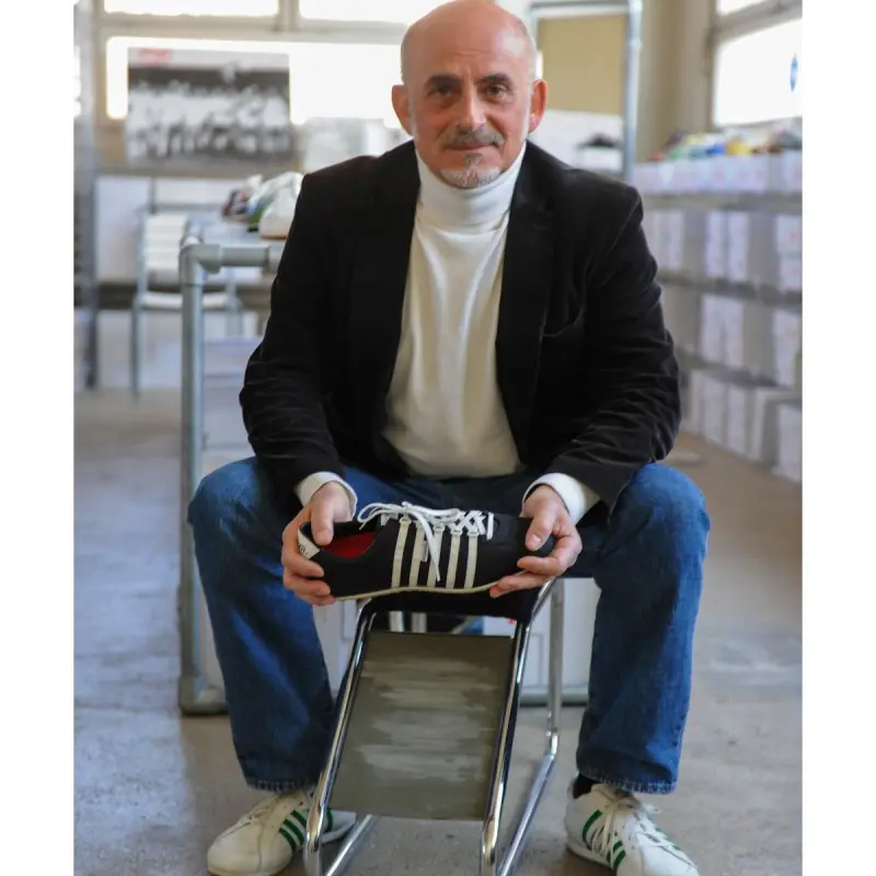 Bild von Roberto Martullo, CEO von Künzli Schuh, sitzend auf einem Stuhl mit einem seiner Schuhe in der Hand
